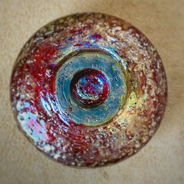 Round red and gold ceramic vase from Nepal with blue ring around the opening